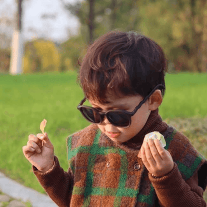 Toddler Boy Wearing A Stylish matte black sunglasses designed for children aged 4-12 years, providing a sleek and versatile accessory that complements any outfit while offering essential UV protection for sunny days.